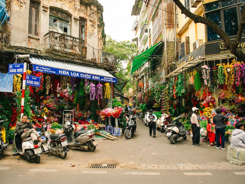 A bustling street in Hanoi, Vietnam, lined with various shops and vibrant storefronts.